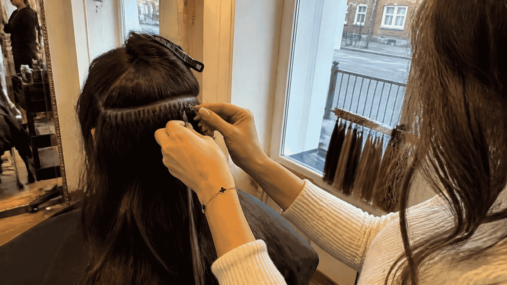 Hairdresser fitting hair extensions on a client at Hair Nova Angel salon in Islington London
